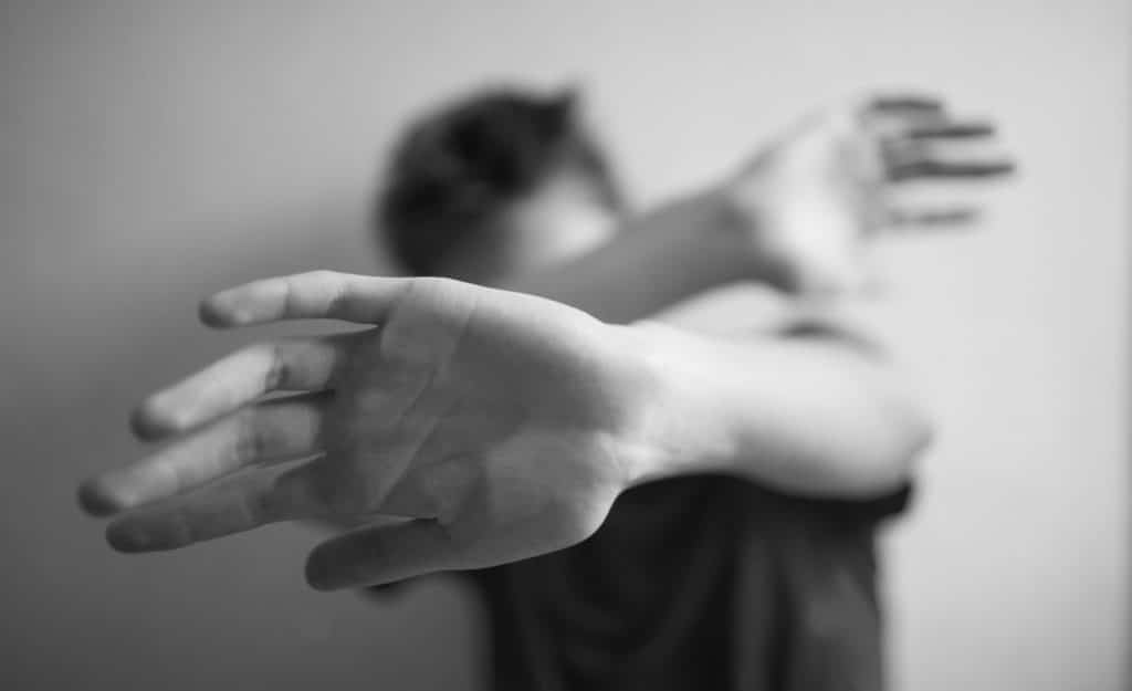 A man covering his face with his arms.