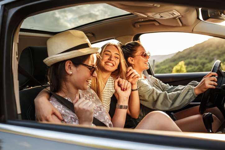 Three young women driving in a car.