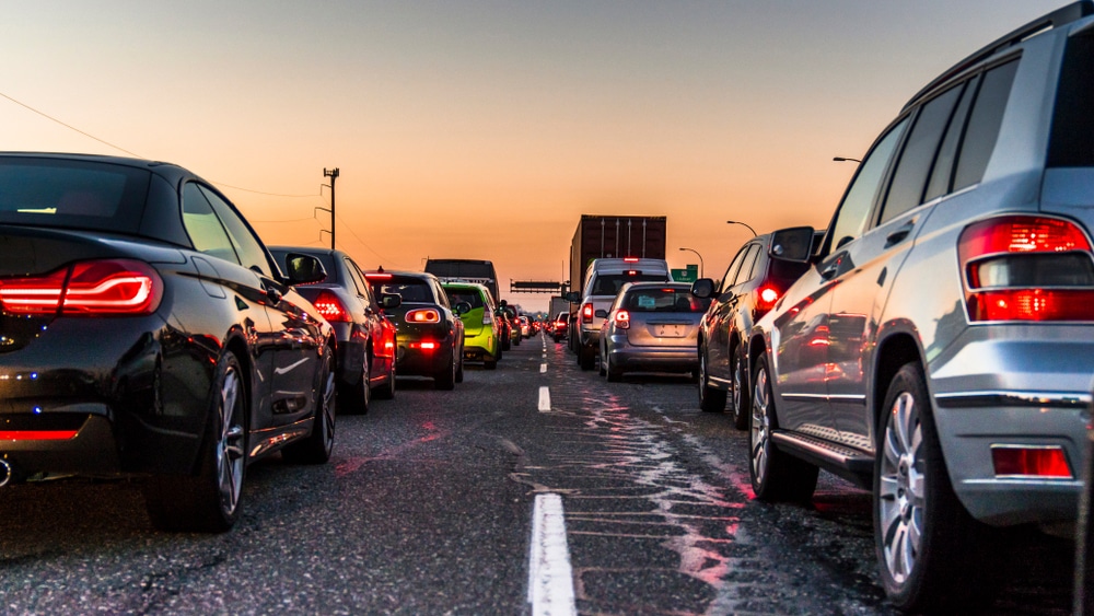 Two lanes of stopped traffic on a highway at sunset