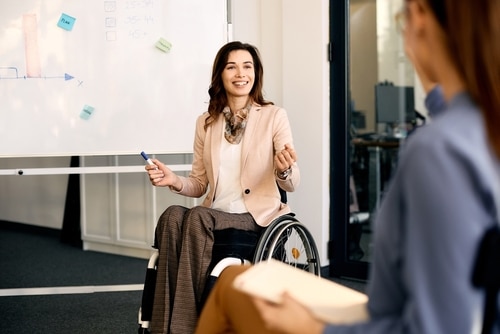 CEO in wheelchair during presentation in meeting room. CEO in wheelchair during presentation in meeting room.