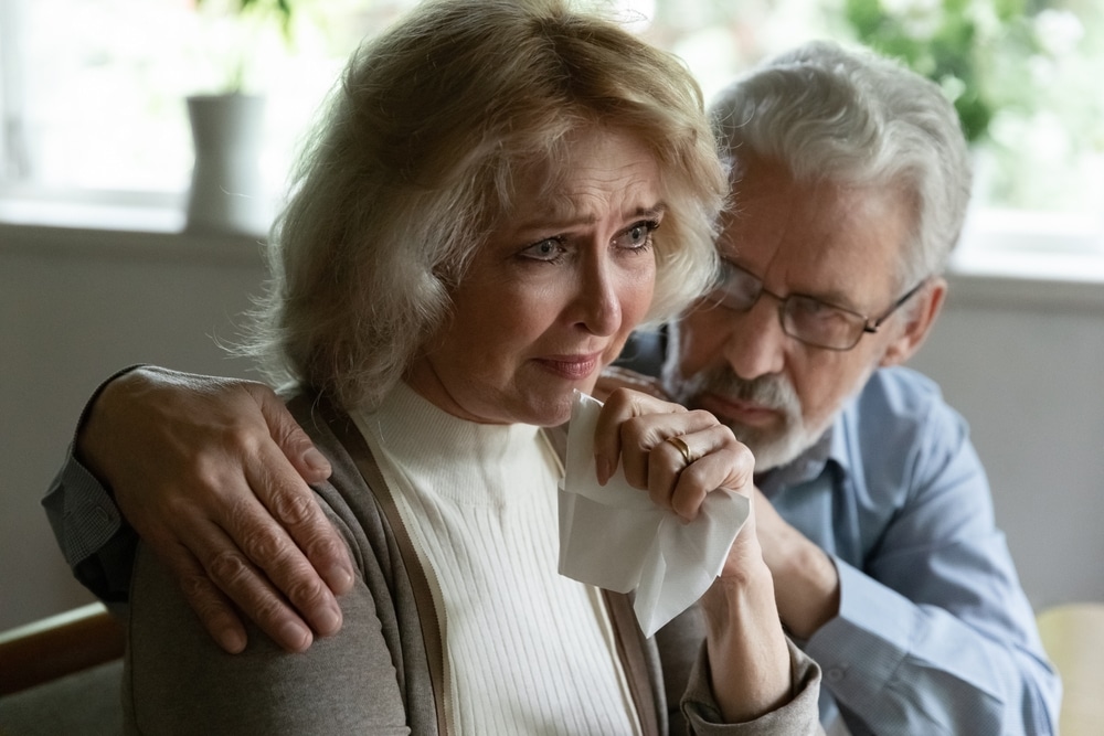 Man hugs and comforts grieving woman who is crying following a wrongful death incident. She is entitled to compensation for her pain and loss