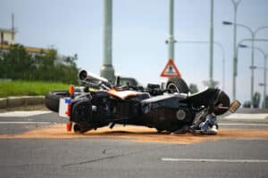A motorcycle overturned and laying in a wreck in the middle of the road after a car accident.