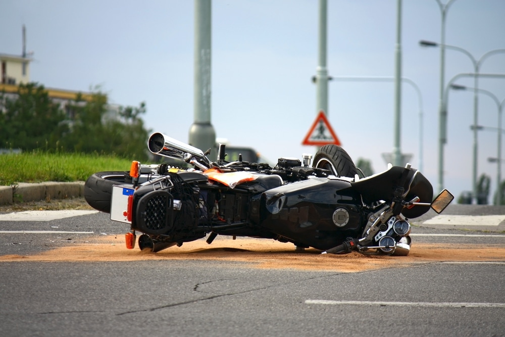 A motorcycle overturned and laying in a wreck in the middle of the road after a car accident. A motorcycle overturned and laying in a wreck in the middle of the road after a car accident.