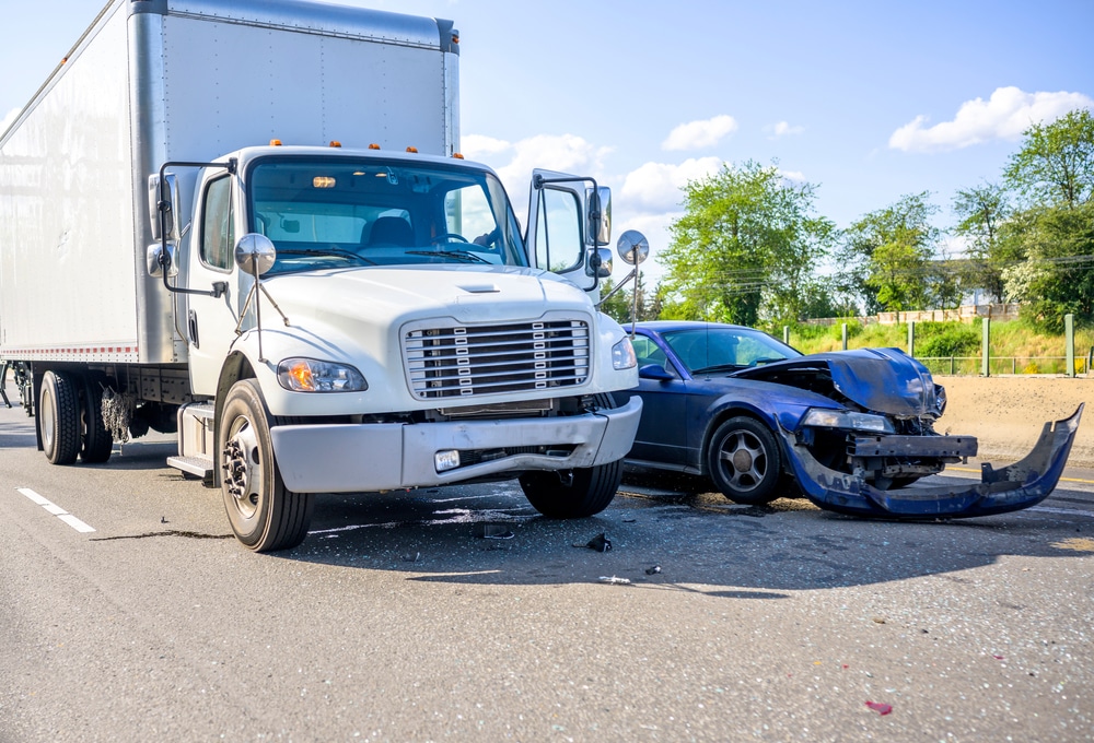 Group of people sitting at a conference table and working on an injury insurance claim. Commercial vehicle collision with a normal, smaller personal vehicle. Unclear who is at fault.