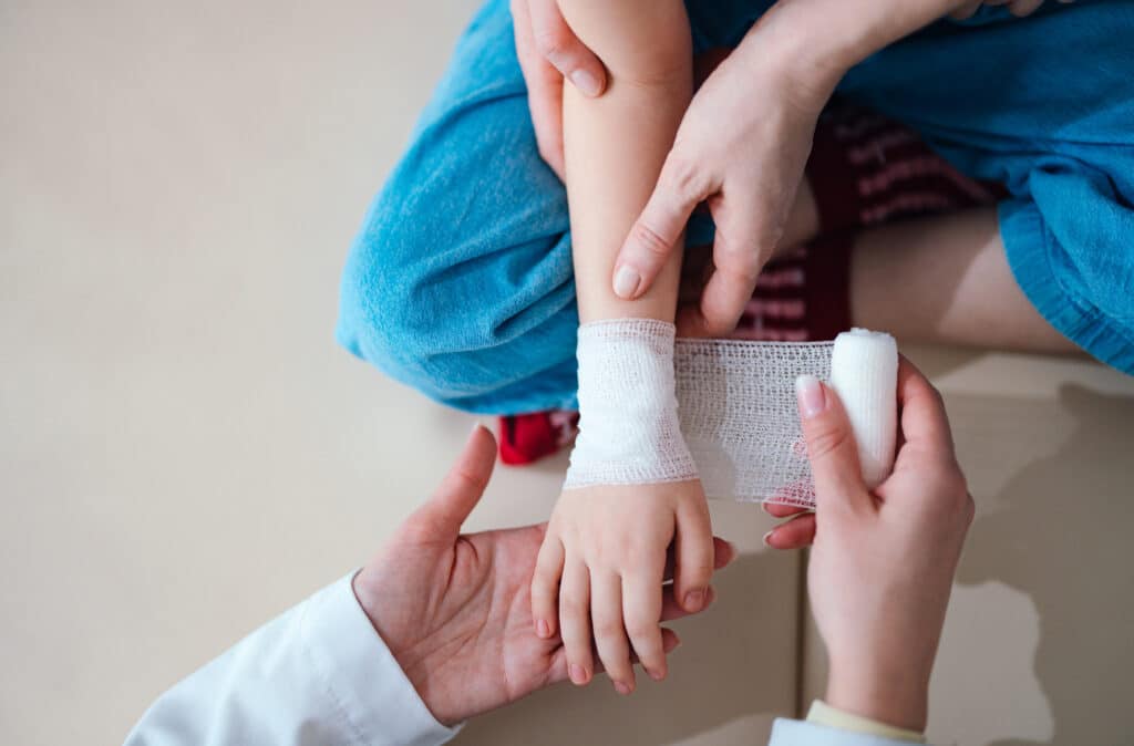 Doctor Treating Child's Injured Hand with Careful Bandaging Child having their hand bandaged after a dog bite.