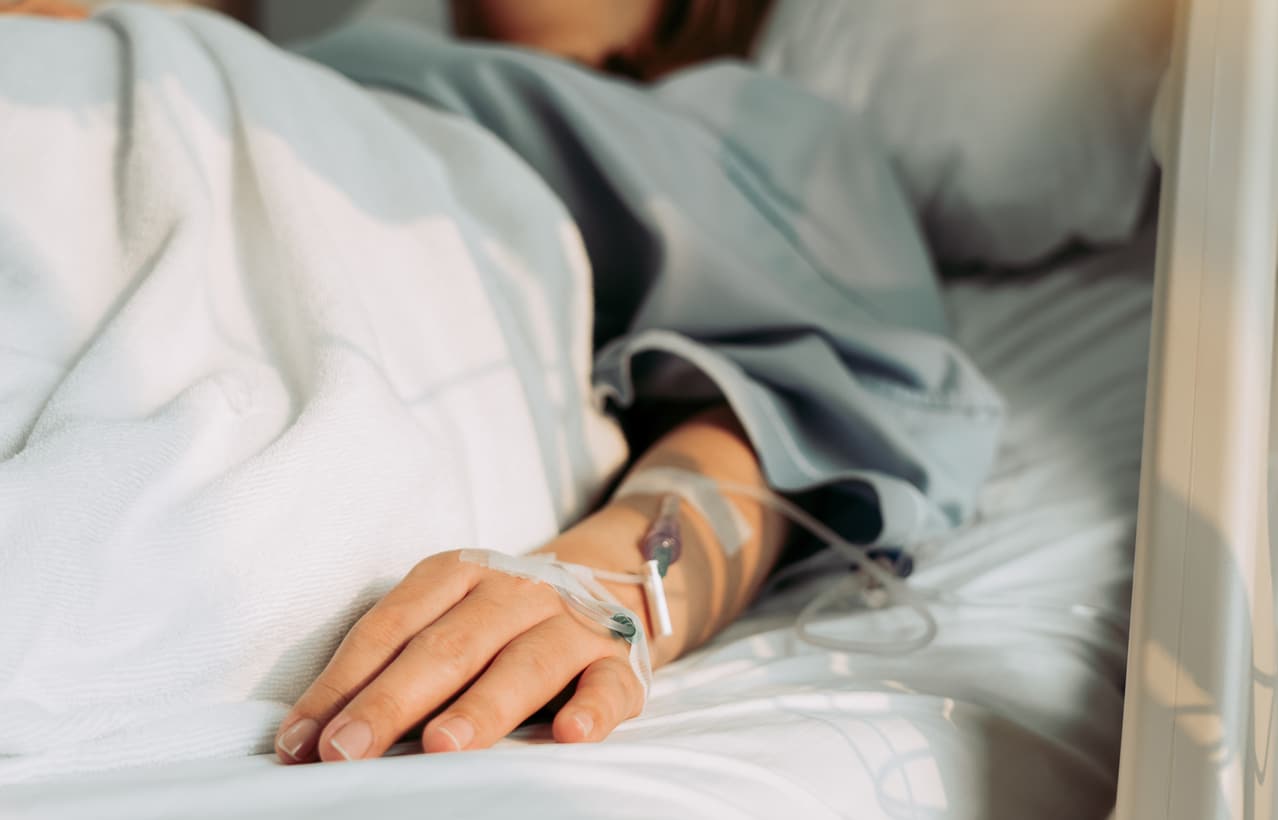 Close-up of a patient in the hospital with an IV placed in their arm, dealing with a missed advanced illness.