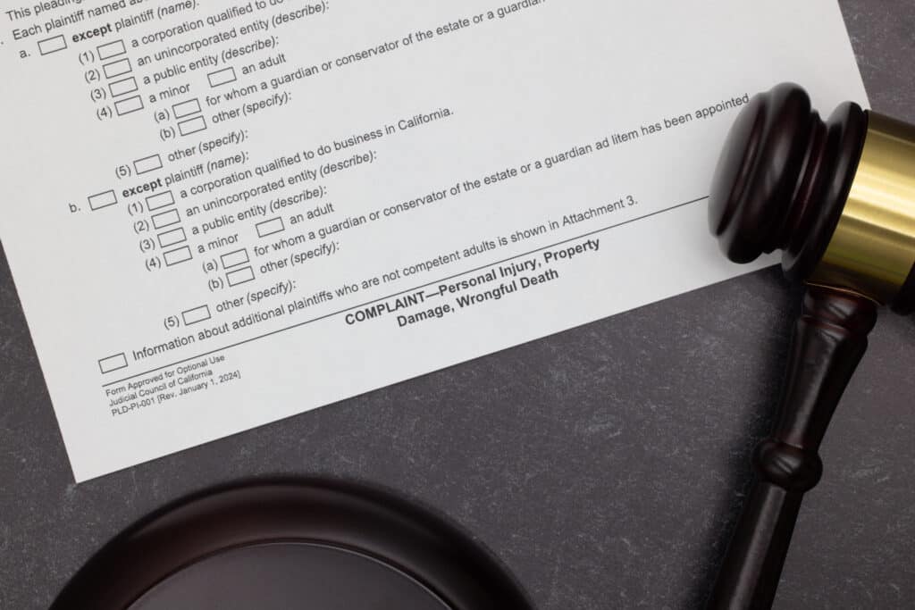Personal Injury, Property Damage, Wrongful Death Complaint legal form with gavel and block on slate desktop Close-up of a wrongful death legal form with a gavel, ready for a wronged family member to seek compensation.